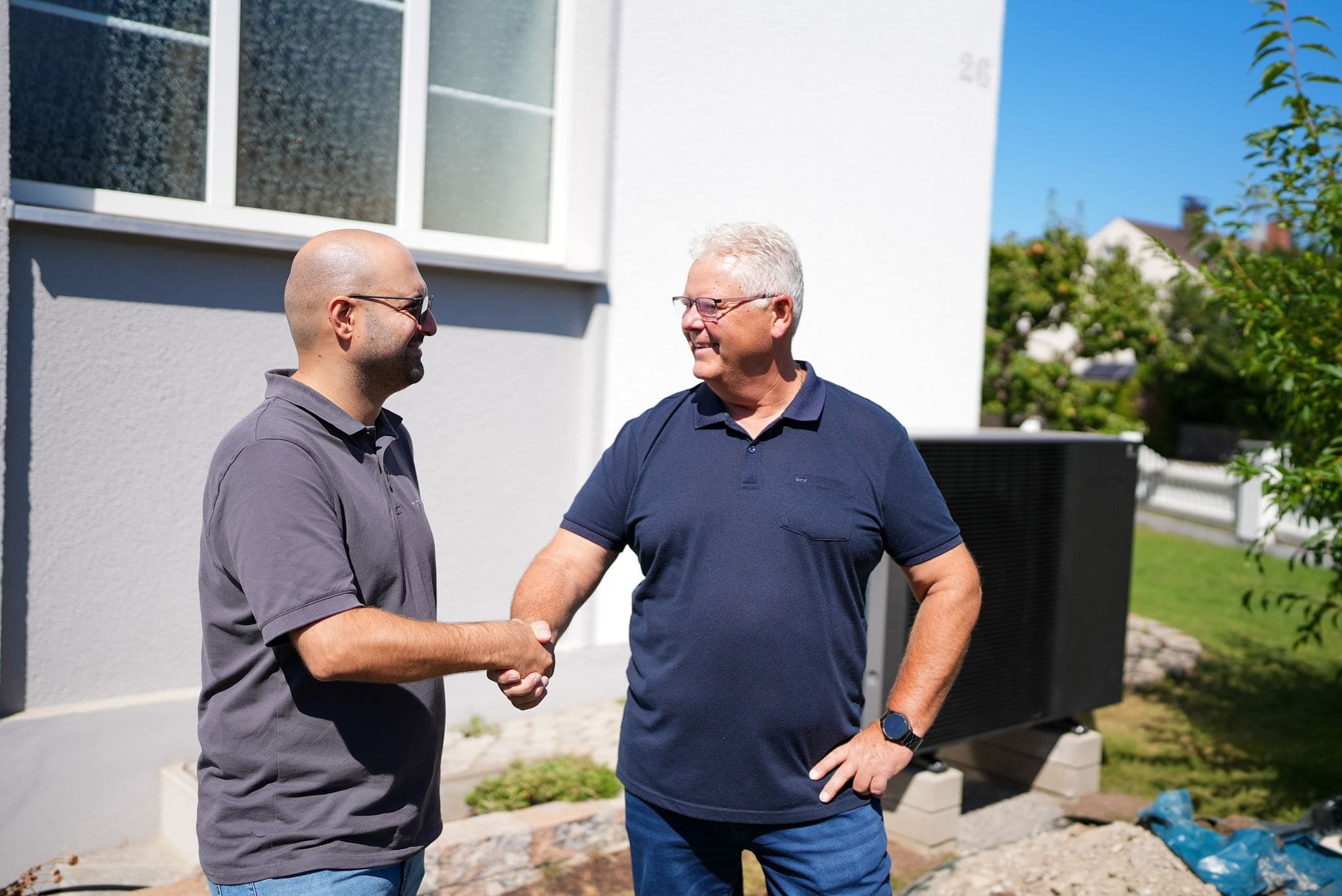 Kunde und Durmus Pekel von HeatPure geben sich vor der neuen Wärmepumpe die Hand