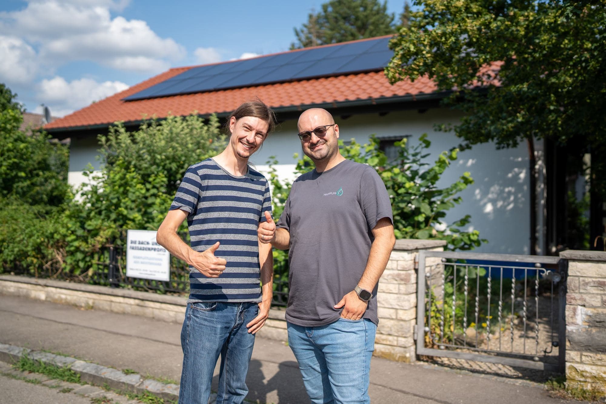 Kunde und Durmus Pekel von HeatPure vor einem Haus mit Photovoltaik und Wärmepumpe